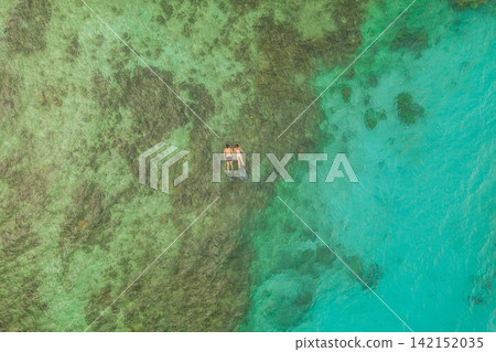 Drone, couple and swimming with nature, vacation and adventure with holiday and Raja Ampat. Aerial view, water and seaside with people and hobby with sunshine and ocean with luxury, active and travel Drone, couple and swimming with nature, vacation and adventure with holiday and Raja Ampat. Aerial view, water and seaside with people and hobby with sunshine and ocean with luxury, active and travel 142152035