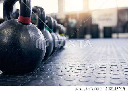 Fitness, kettlebell and weights on floor of gym for training, wellness or workout with space. Background, metal equipment in health club and exercise for action, physical improvement or strength Fitness, kettlebell and weights on floor of gym for training, wellness or workout with space. Background, metal equipment in health club and exercise for action, physical improvement or strength 142152049