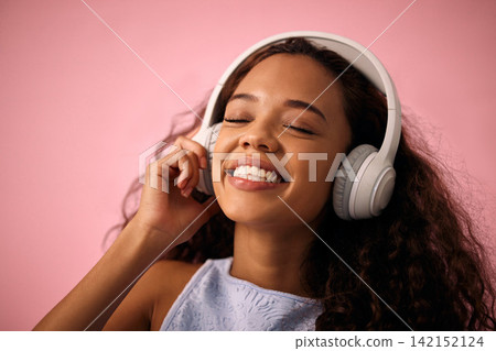 Happy girl, relax and listening to music with headphones for jazz or beats on a pink studio background. Female person enjoying podcast, audio streaming or sound with smile for radio, song or playlist Happy girl, relax and listening to music with headphones for jazz or beats on a pink studio background. Female person enjoying podcast, audio streaming or sound with smile for radio, song or playlist 142152124