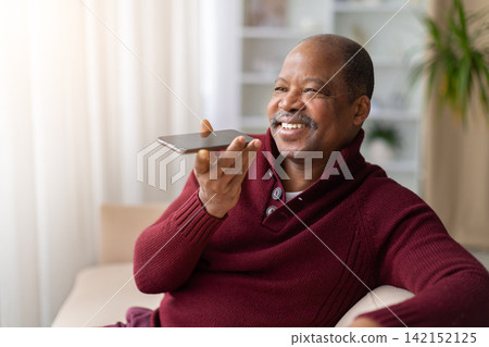 Cheerful mature black man using voice assistant on smartphone at home Cheerful mature black man using voice assistant on smartphone at home 142152125