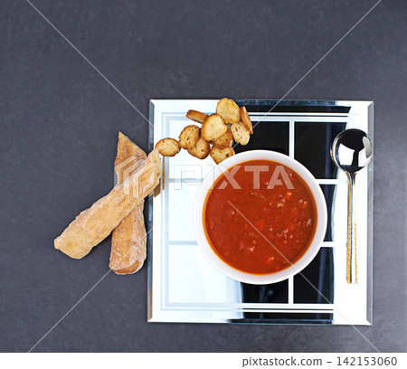 Tomato, soup and bread on menu in restaurant with bowl of healthy food for diet and nutrition benefits. Dinner, dish and luxury appetizer course in fine dining kitchen with breadsticks on plate Tomato, soup and bread on menu in restaurant with bowl of healthy food for diet and nutrition benefits. Dinner, dish and luxury appetizer course in fine dining kitchen with breadsticks on plate 142153060