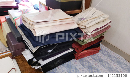 房間裡堆放著正在整理的日本服裝和和服。 房間裡堆放著正在整理的日本服裝和和服。 142153106