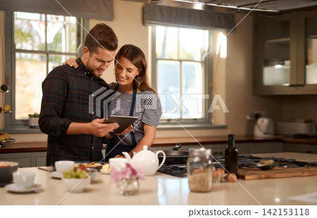 Couple, cooking and tablet for online recipe in home or ingredients on digital food app, meal or internet. Man, woman and happy in kitchen for wellness nutrition or dinner together, website or health Couple, cooking and tablet for online recipe in home or ingredients on digital food app, meal or internet. Man, woman and happy in kitchen for wellness nutrition or dinner together, website or health 142153118