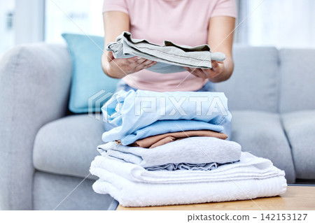 Folding laundry, person and hands in living room on couch, cotton and fabric clothing. Organizing washing, housekeeper and spring cleaning in lounge for routine, wellness and morning on home sofa Folding laundry, person and hands in living room on couch, cotton and fabric clothing. Organizing washing, housekeeper and spring cleaning in lounge for routine, wellness and morning on home sofa 142153127