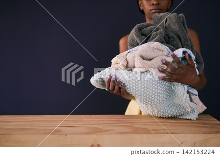 African woman, clean laundry and fresh in home with mockup and charity donation by dark background. Black person, fabric care and natural detergent by wood table for house chores and weekend routine African woman, clean laundry and fresh in home with mockup and charity donation by dark background. Black person, fabric care and natural detergent by wood table for house chores and weekend routine 142153224