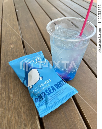 在夏日的木質露臺上,享用一杯清爽的藍色飲品和鹹香草冰淇淋。 在夏日的木質露臺上,享用一杯清爽的藍色飲品和鹹香草冰淇淋。 142153231