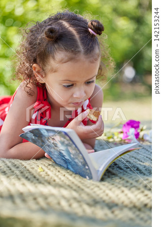 Girl, child and book on picnic blanket for reading with eating cookies in park to relax with learning. Kid, story and biscuit on lawn for development, education and literacy with sunshine in nature Girl, child and book on picnic blanket for reading with eating cookies in park to relax with learning. Kid, story and biscuit on lawn for development, education and literacy with sunshine in nature 142153244