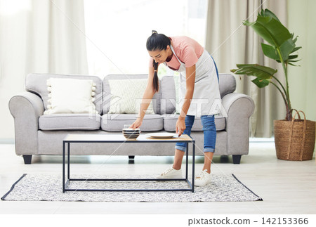 Woman, dishes and cleaning by table in home with domestic services, job and hygiene for dirt in lounge. Girl, maid or cleaner with crockery, plate and housework in living room with apron for routine Woman, dishes and cleaning by table in home with domestic services, job and hygiene for dirt in lounge. Girl, maid or cleaner with crockery, plate and housework in living room with apron for routine 142153366