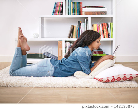 Black woman, relax and online on floor with tablet for entertainment, social media or streaming trending videos. Person, digital technology and internet for connectivity and scroll on website. Black woman, relax and online on floor with tablet for entertainment, social media or streaming trending videos. Person, digital technology and internet for connectivity and scroll on website. 142153873