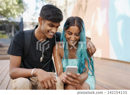 Couple, earphones and student with mobile phone for social media, meme or watching video on campus. Headphones, happy man and woman with smartphone for internet search, online app or web browsing Couple, earphones and student with mobile phone for social media, meme or watching video on campus. Headphones, happy man and woman with smartphone for internet search, online app or web browsing 142154133