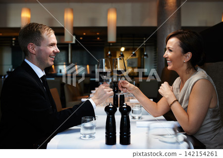 Couple, dinner and wine glass for cheers at table, celebration and anniversary in restaurant. Happy, alcohol and smile for toast with man and wife, marriage and romantic for luxury date at night Couple, dinner and wine glass for cheers at table, celebration and anniversary in restaurant. Happy, alcohol and smile for toast with man and wife, marriage and romantic for luxury date at night 142154261