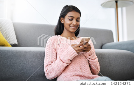 Relax, floor and Indian woman in living room with phone for social media, networking or streaming. Happy, scroll and girl in lounge on smartphone for communication, online chat or post search in home 142154271
