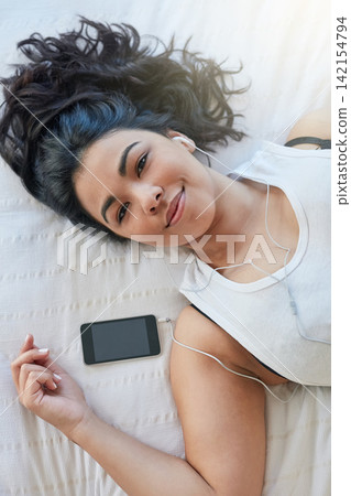 Woman, earphone and music in bed with cellphone, audio or rest in home. Calm, portrait and peace in bedroom for lazy day on weekend with podcast, comfortable and sleep or self care for female person Woman, earphone and music in bed with cellphone, audio or rest in home. Calm, portrait and peace in bedroom for lazy day on weekend with podcast, comfortable and sleep or self care for female person 142154794