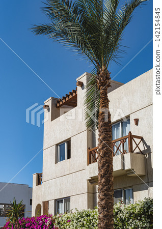 Modern apartment house in traditional Middle East style with palm trees and front yard garden. Modern apartment house in traditional Middle East style with palm trees and front yard garden. 142154845