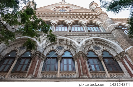Facade and stone carvings of the heritage building with big arched windows Facade and stone carvings of the heritage building with big arched windows 142154874