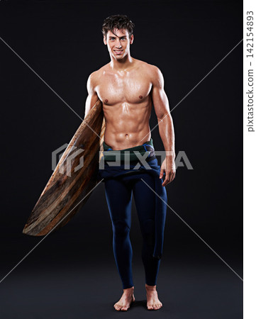 Young surfer and vintage board in studio and dark with body, stomach and strong or healthy. Male wave rider, backdrop or wood or retro accessory in portrait for sports, fitness or confidence at night Young surfer and vintage board in studio and dark with body, stomach and strong or healthy. Male wave rider, backdrop or wood or retro accessory in portrait for sports, fitness or confidence at night 142154893
