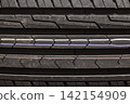 A close-up of a car tire tread, revealing a detailed view of the rubber pattern. Macro photography of the tread of a new car tire, showing a clearly defined pattern. 142154909