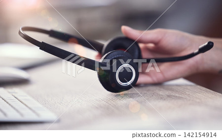 Call center, desk and hand on person with headphones for telemarketing, sales call and consulting. CRM business, office and consultant with headset on table for customer service, ecommerce and help Call center, desk and hand on person with headphones for telemarketing, sales call and consulting. CRM business, office and consultant with headset on table for customer service, ecommerce and help 142154914