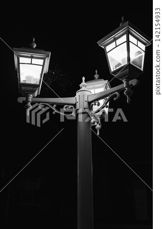 Vintage street lamp with three glowing lights at night, illuminated lantern against dark sky Vintage street lamp with three glowing lights at night, illuminated lantern against dark sky 142154933