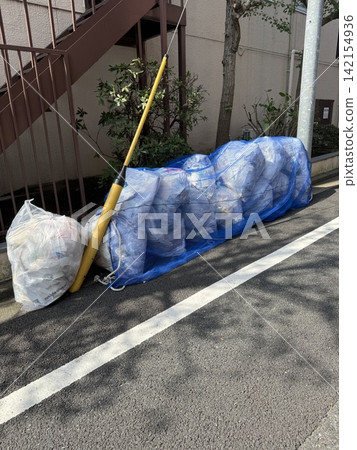 東京的一個垃圾收集點被藍色防護網覆蓋,以防止烏鴉破壞。 東京的一個垃圾收集點被藍色防護網覆蓋,以防止烏鴉破壞。 142154936