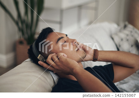 Home, relax and man with headphones, listening to music and peaceful with wellness and zen. Person, apartment and guy with headset and streaming podcast with break and resting with sound and song 142155007