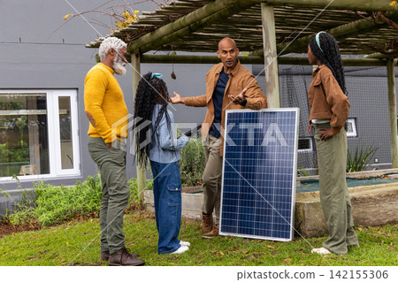 African American family at pergola, teen nearby, child holding tablet, man gesturing by solar panel African American family at pergola, teen nearby, child holding tablet, man gesturing by solar panel 142155306