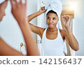 Black woman, bathroom and mirror with towel for hair care treatment for morning routine, reflection or home. Female person, health and shampoo cleaning in apartment for texture, growth or wellness 142156437