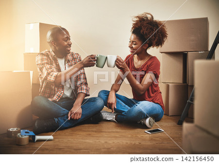 Black couple, cheers and cup on floor of new house with bonding, support and happy for coffee break from moving. People, success and toast for property investment, dream home or relocation with boxes Black couple, cheers and cup on floor of new house with bonding, support and happy for coffee break from moving. People, success and toast for property investment, dream home or relocation with boxes 142156450