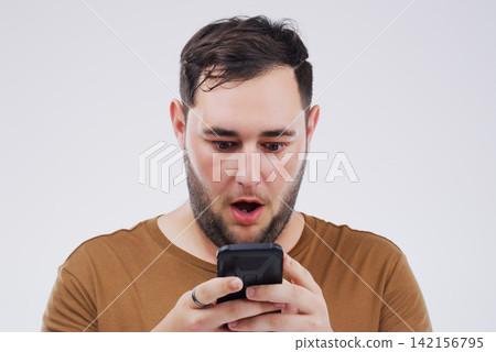Man, wow face and smartphone on studio background for reading website with omg expression, social media and online scam. Male person, mobile and surprise by grey backdrop for news website and shocked Man, wow face and smartphone on studio background for reading website with omg expression, social media and online scam. Male person, mobile and surprise by grey backdrop for news website and shocked 142156795