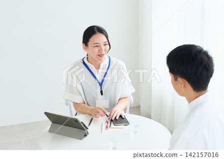 A female staff member and a man explain. 142157016