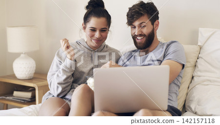 Happy, couple and relaxing with laptop on bed for bonding by watching movie, film and comedy together at house. Man, woman and care with popcorn in bedroom for streaming funny show as entertainment Happy, couple and relaxing with laptop on bed for bonding by watching movie, film and comedy together at house. Man, woman and care with popcorn in bedroom for streaming funny show as entertainment 142157118