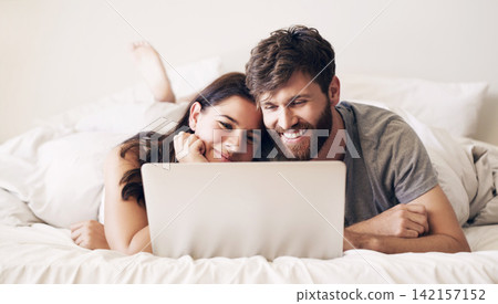 Embrace, couple and relaxing with laptop on bed for bonding by watching movie, film and comedy together at house. Man, woman and care with smile in bedroom for streaming funny show as entertainment Embrace, couple and relaxing with laptop on bed for bonding by watching movie, film and comedy together at house. Man, woman and care with smile in bedroom for streaming funny show as entertainment 142157152