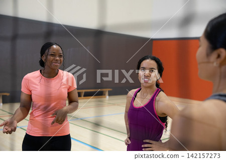 Diverse female friends standing and talking on gym court with painted lines, wearing sportswear 142157273
