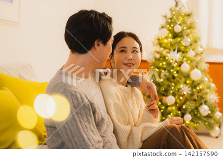 A couple relaxing in their living room on Christmas Day. A couple relaxing in their living room on Christmas Day. 142157590