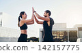 Man, woman and high five for fitness in city, workout and exercise with partnership for training. Friends, teamwork and male personal trainer outdoor for wellness, success and teamwork in New York 142157775