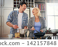 Couple, stove and cooking while laughing in home, love and care for food or meal in kitchen. Happy people, pancakes and pan for breakfast and joke for bonding, nutrition and comedy in marriage 142157848