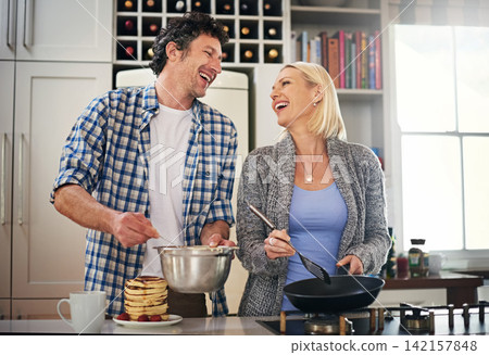 Couple, stove and cooking while laughing in home, love and care for food or meal in kitchen. Happy people, pancakes and pan for breakfast and joke for bonding, nutrition and comedy in marriage Couple, stove and cooking while laughing in home, love and care for food or meal in kitchen. Happy people, pancakes and pan for breakfast and joke for bonding, nutrition and comedy in marriage 142157848