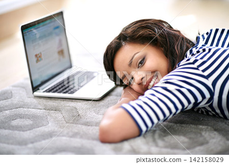 Portrait of girl, laptop screen and lying on floor carpet at home for movie break, relax and rest with smile. Technology, connectivity and computer watch, online videos and female person in house 142158029