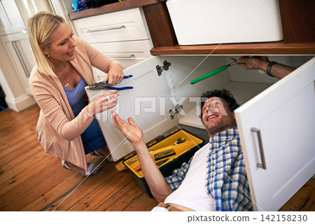 Lady, help and handyman with tools for fixing home basin, drain or broken interior sewer. Plumber, working and woman watching male person repair for burst pipe, sink leaks and kitchen maintenance Lady, help and handyman with tools for fixing home basin, drain or broken interior sewer. Plumber, working and woman watching male person repair for burst pipe, sink leaks and kitchen maintenance 142158230