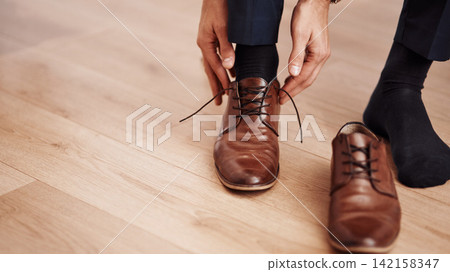 Dressing, shoes and hands of business man in home getting ready for work, career and job. Corporate, morning routine and feet of worker prepare with trendy, professional fashion and formal style Dressing, shoes and hands of business man in home getting ready for work, career and job. Corporate, morning routine and feet of worker prepare with trendy, professional fashion and formal style 142158347