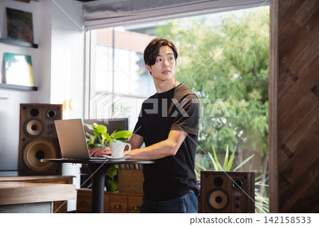 一位年輕的商人正在時尚的共享辦公空間使用站立式辦公桌工作。 142158533