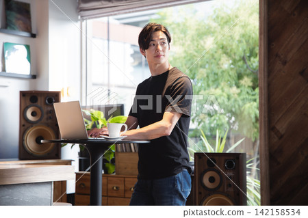 一位男性IT工程師使用站立式辦公桌來專注於處理電腦工作。 142158534