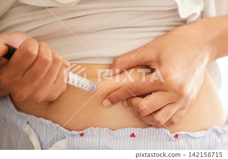 Woman, hands and insulin injection in stomach for diabetes, medical condition or IVF treatment at home. Needle, medication and syringe for health, wellness and home care with medicine for blood sugar Woman, hands and insulin injection in stomach for diabetes, medical condition or IVF treatment at home. Needle, medication and syringe for health, wellness and home care with medicine for blood sugar 142158715