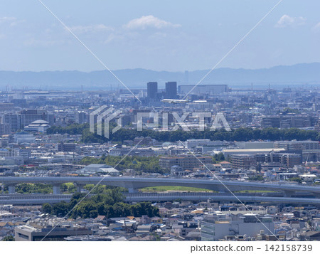 A cityscape with a passenger plane flying overhead. A cityscape with a passenger plane flying overhead. 142158739