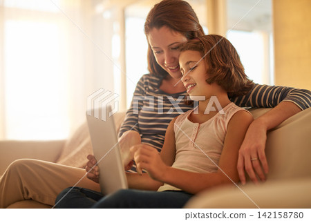 Mother, child and sofa with tablet for streaming movies, happiness and bonding together in living room. Family, mom and young girl with technology for e learning, education or social media in home Mother, child and sofa with tablet for streaming movies, happiness and bonding together in living room. Family, mom and young girl with technology for e learning, education or social media in home 142158780