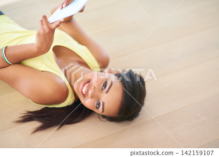 Portrait, young woman and tablet on floor with happy for connectivity, streaming or online shopping. Female person, technology and smile for social media, e learning or gaming in chat or video call Portrait, young woman and tablet on floor with happy for connectivity, streaming or online shopping. Female person, technology and smile for social media, e learning or gaming in chat or video call 142159107