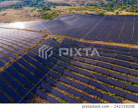 Solar panels cover large open area in a renewable energy field under clear sky during daytime Solar panels cover large open area in a renewable energy field under clear sky during daytime 142159206