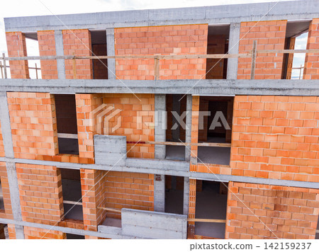 Construction of a building with brick walls and concrete structure during the day Construction of a building with brick walls and concrete structure during the day 142159237
