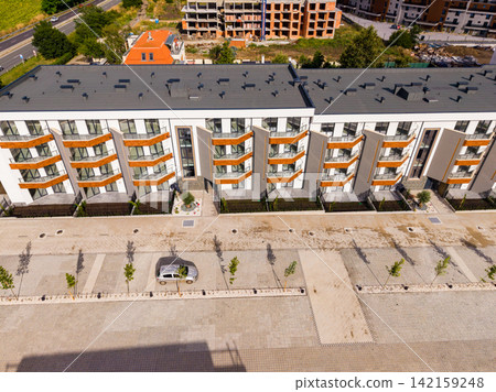 New apartment buildings under construction along a street in a developing urban area with vehicles parked nearby New apartment buildings under construction along a street in a developing urban area with vehicles parked nearby 142159248