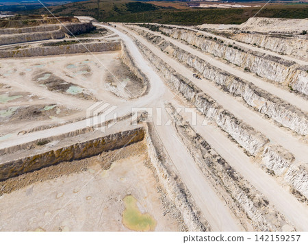 Quarry site showing deep excavations and paths in an open area with stone extraction activity ongoing Quarry site showing deep excavations and paths in an open area with stone extraction activity ongoing 142159257